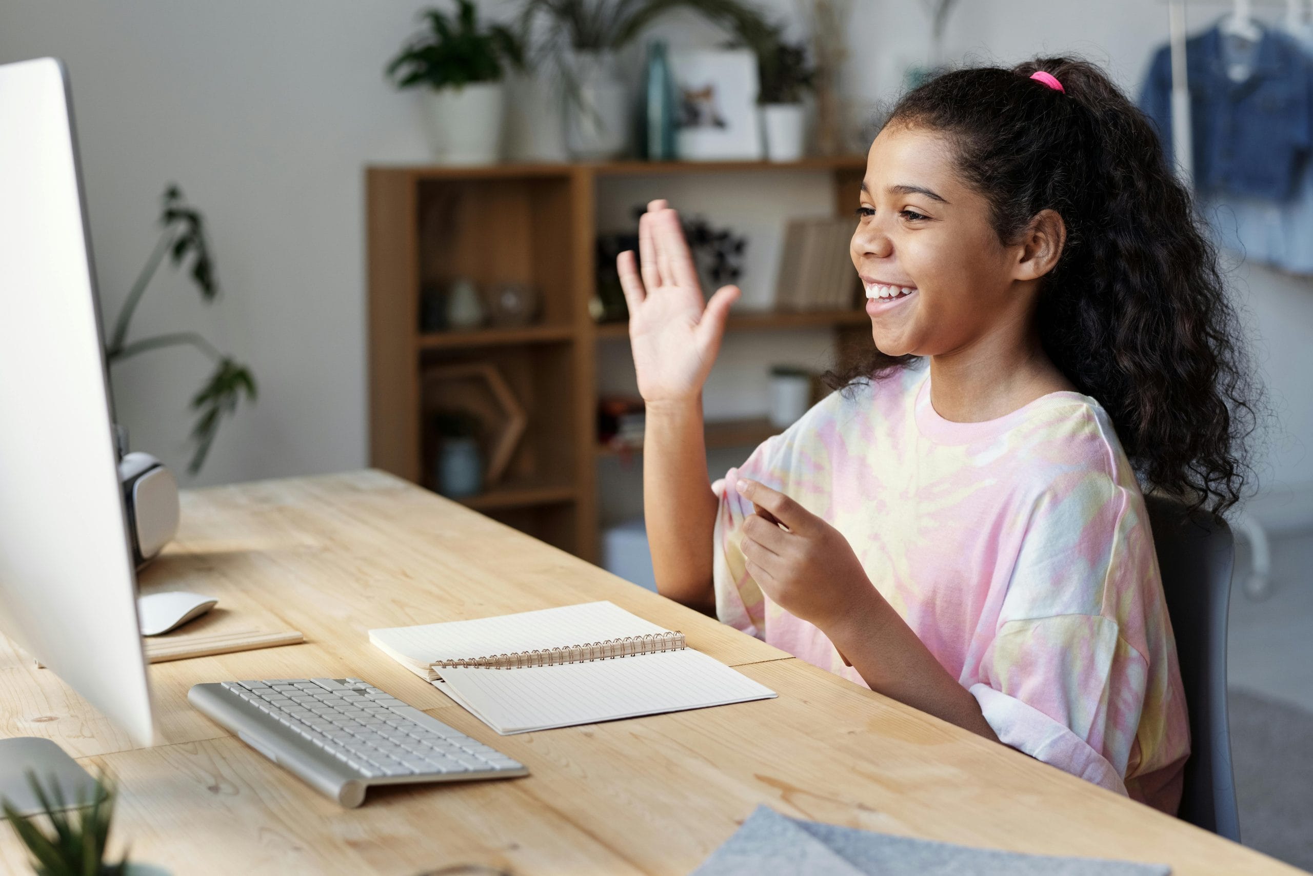 A child waving at the screen during an online therapy session at home