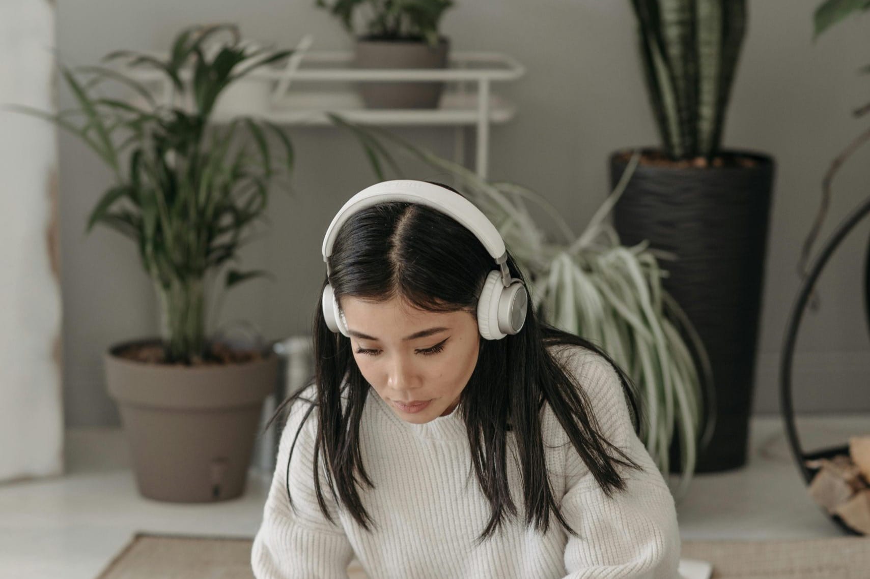 An adult sitting quietly at home with headphones, during an online session